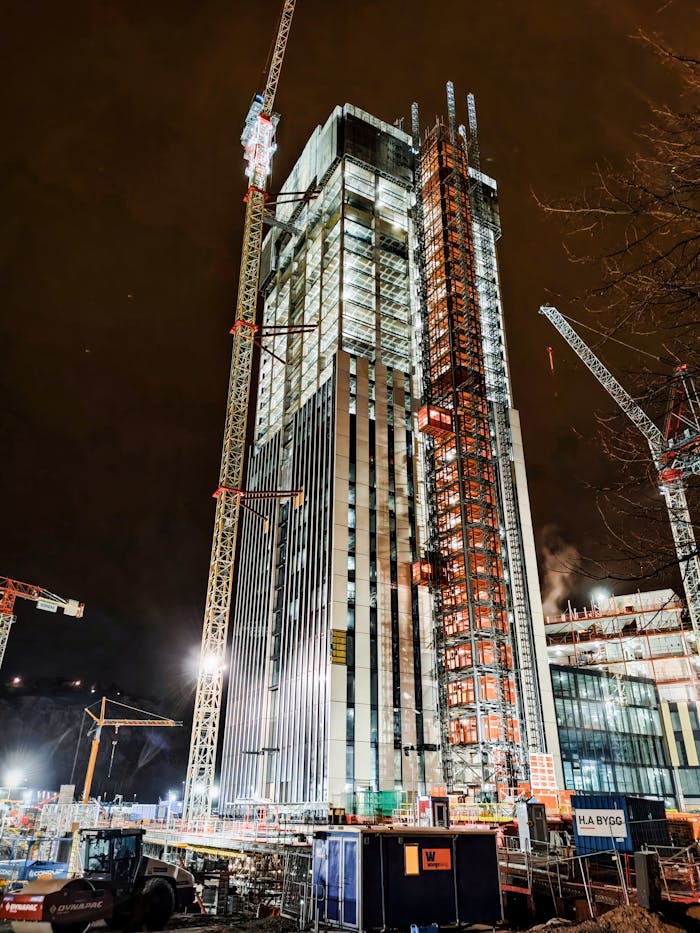 gallery-3 A modern skyscraper under construction at night in Lindholmen, Sweden, illuminated by cranes and lights.