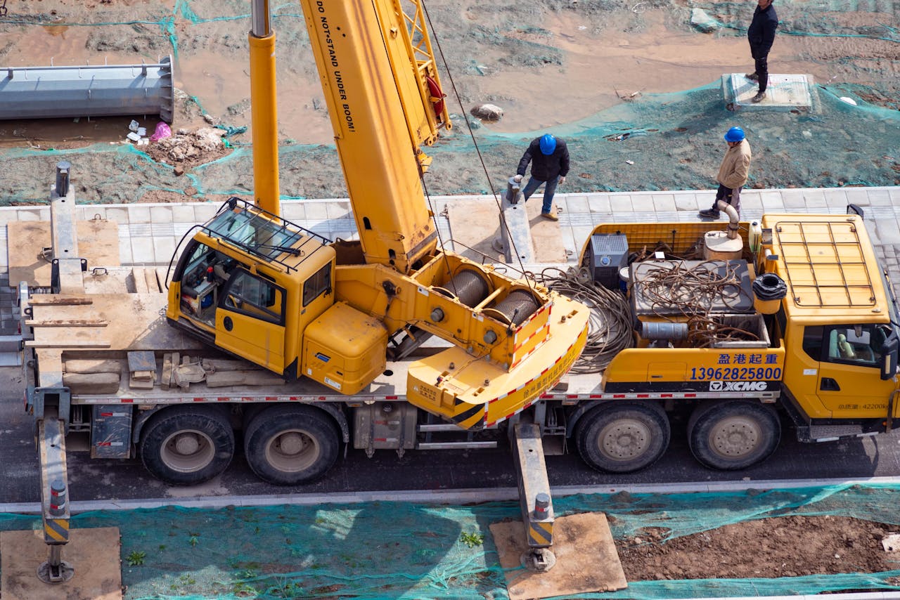 services-03 Aerial shot of a construction site showcasing a yellow crane and workers in action.