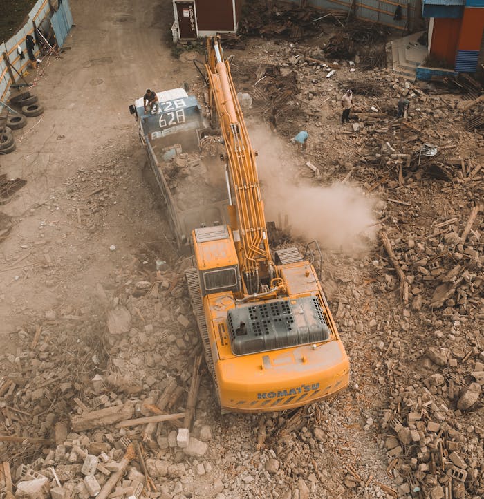 gallery-5 Aerial view of an excavator loading debris at a construction site with workers nearby.